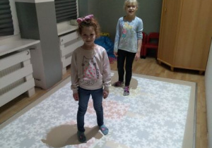 Dziewczynki stoją na podłodze interaktywnej. Grają w grę Rozmrażamy lody